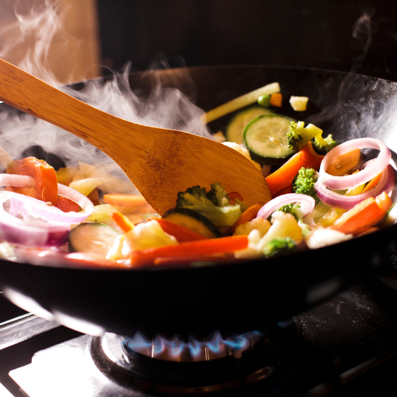 stir fry pan with vegetables and wooden utensil
