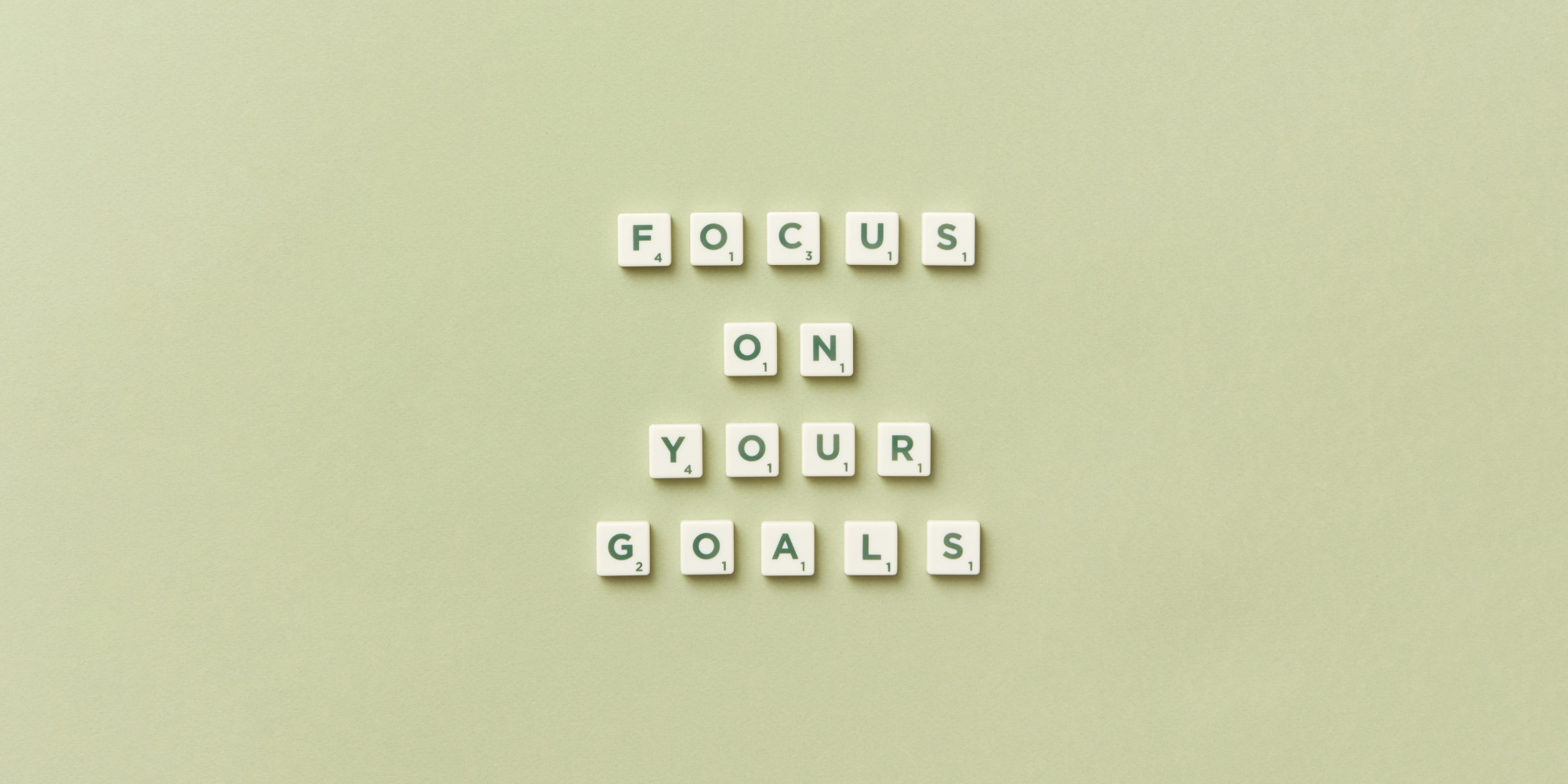 Against a pale green background are square letters arranged to read "Focus/on/your/goals"
