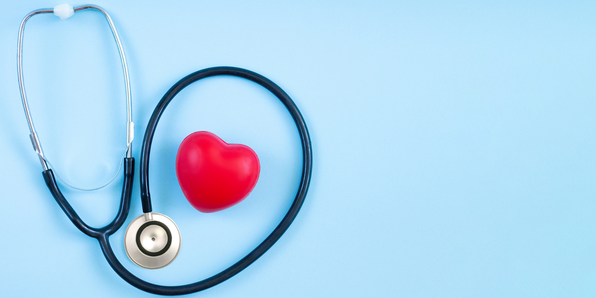 Stethoscope against a pale blue background coiled around a plush heart shape